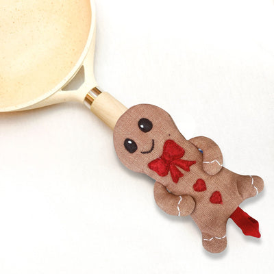 Gingerbread man-shaped spoon rest with a red bow on a white background