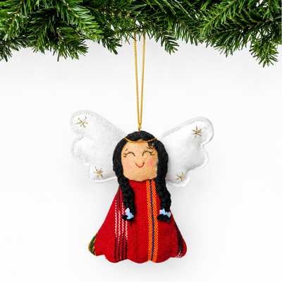Decorative angel ornament with long hair and red outfit hanging from a tree branch.