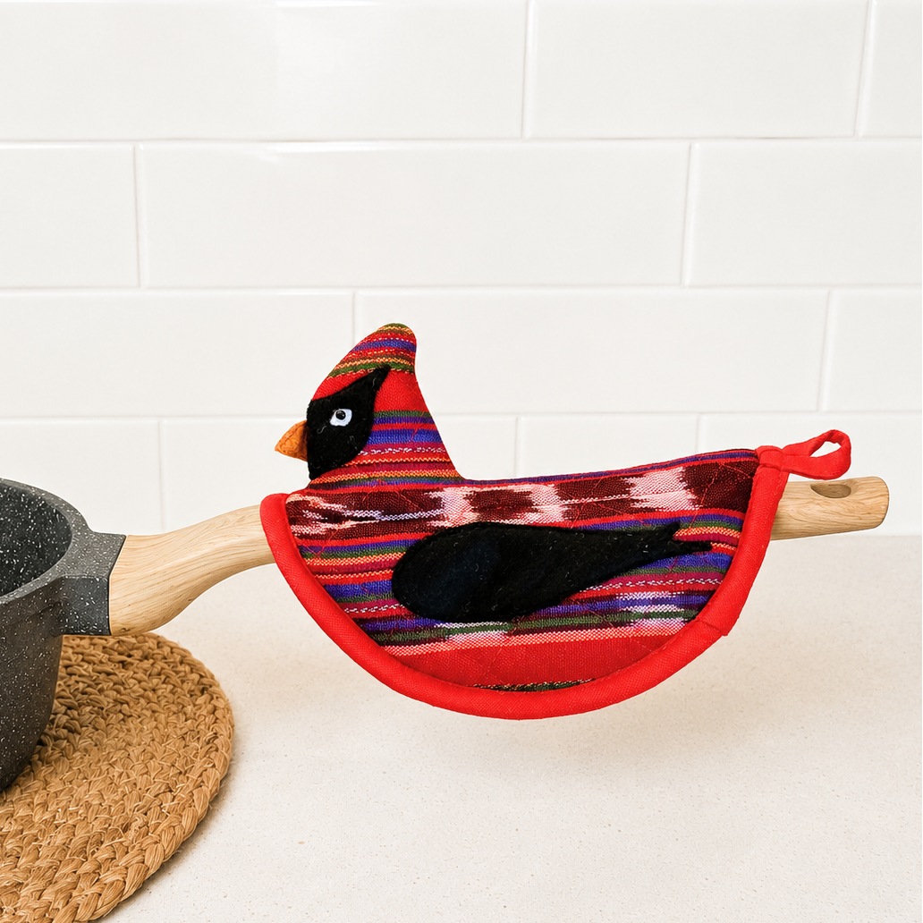 Colorful bird-shaped potholder on a pot handle with a white tiled wall background