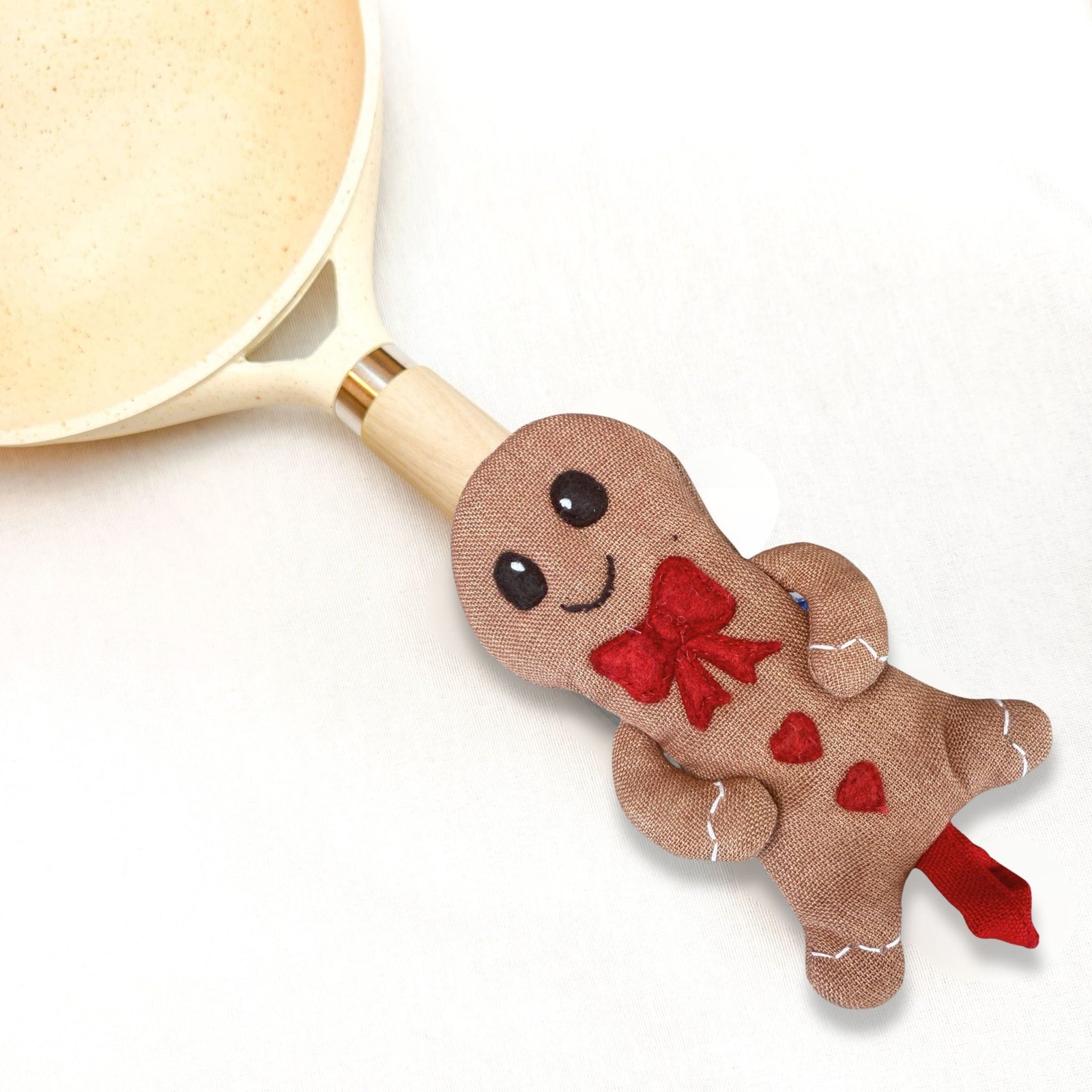 Gingerbread man-shaped spoon rest with a red bow on a white background
