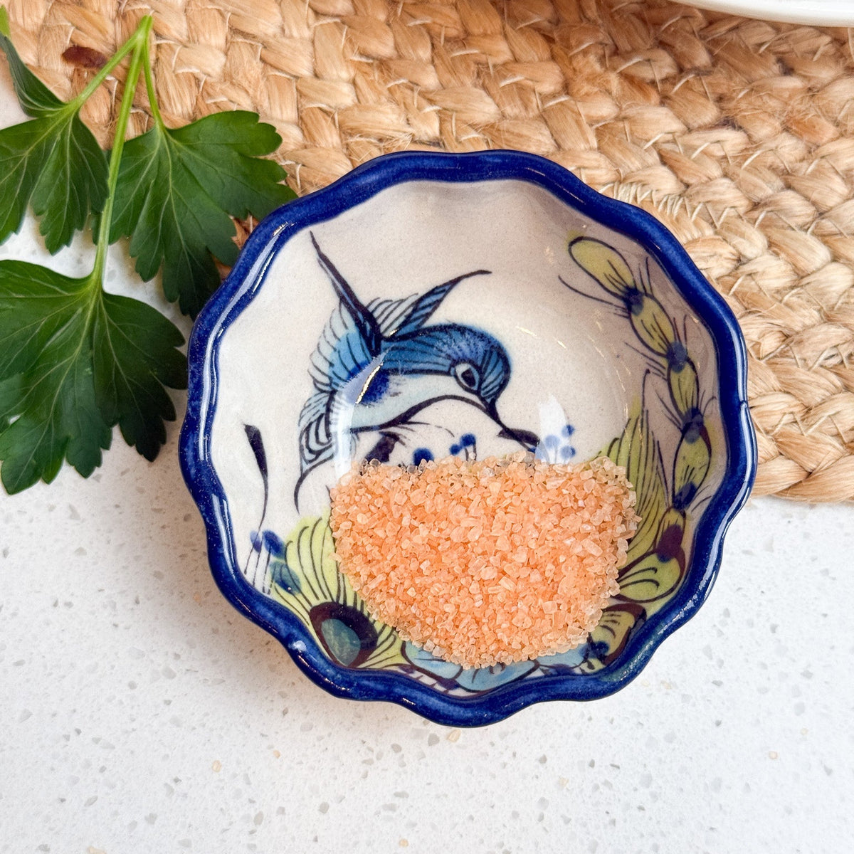 Decorative ceramic bowl with blue rim and fish design on a white surface with a woven mat background.