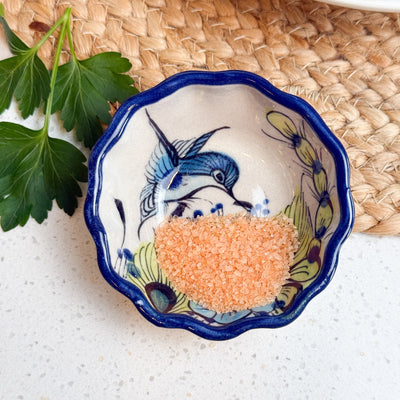 Decorative ceramic bowl with blue rim and fish design on a white surface with a woven mat background.