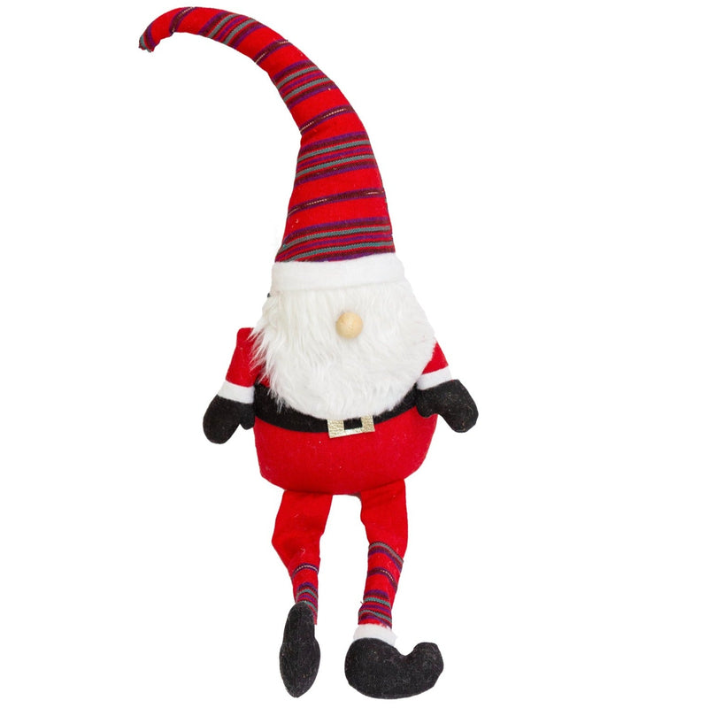 Decorative gnome with striped hat on a shelf with Christmas decorations and a snowy view outside.